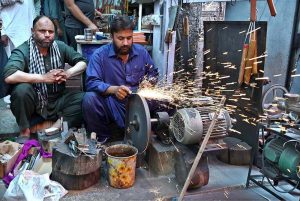 Blacksmith busy sharpen the knife to be used for slaughtering sacrificial animals during Eidul Azha