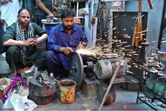 Blacksmith busy sharpen the knife to be used for slaughtering sacrificial animals during Eidul Azha