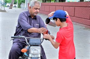 A young volunteer serves chilled drinks to motorcyclist and passersby on the roadside in memory of the martyrs of Karbala.