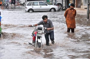 female commuter rides an electric scooter through heavy rain as the monsoon spell hits the city.