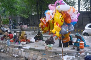 A gypsy child sells balloons under the bridge during a rainy day in the city.