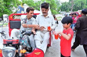 A young volunteer serves chilled drinks to motorcyclist and passersby on the roadside in memory of the martyrs of Karbala.