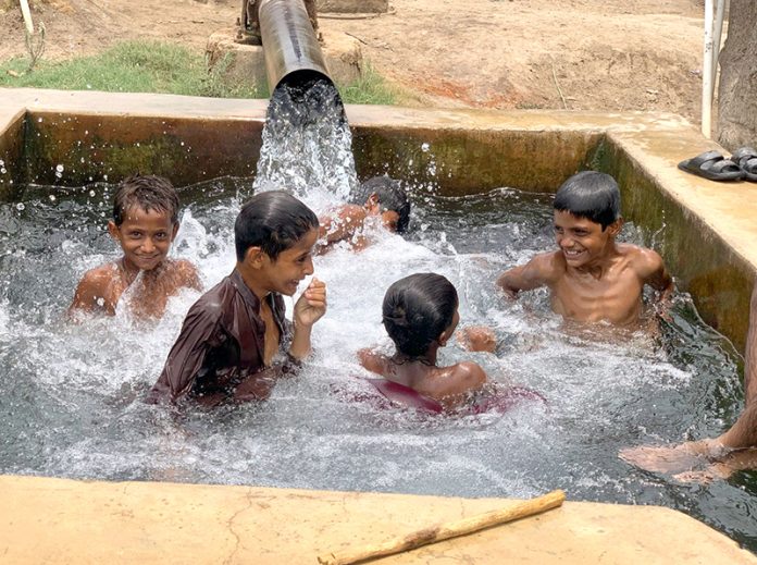 Village children enjoy bathing in a tube well pond to get relief from the scorching heat at Yousfani village
