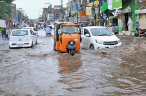 Vehicles navigate through a rain-flooded road, highlighting the challenges faced by commuters during heavy monsoon showers in the city.