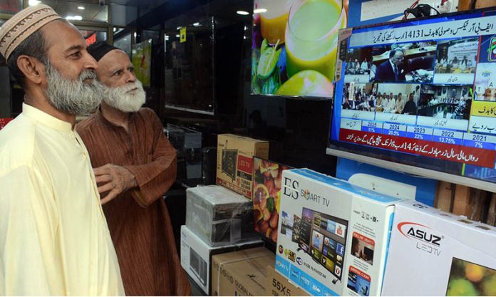 Citizens watching the 2025-26 federal budget live on television screen