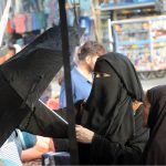 Women purchasing an umbrella to protect herself from scorching heat from a vendor