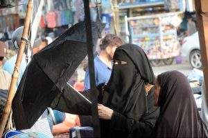 Women purchasing an umbrella to protect herself from scorching heat from a vendor