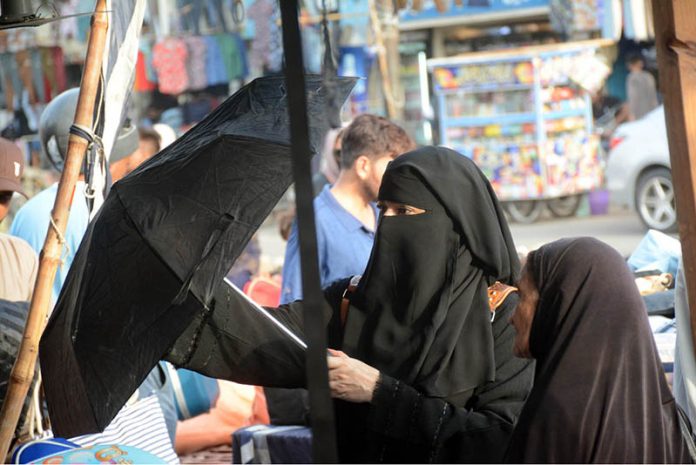 Women purchasing an umbrella to protect herself from scorching heat from a vendor