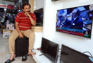 Citizens watching the 2025-26 federal budget live on television screen