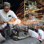A man sharpens knives to slaughter sacrificial animals in connection with upcoming Eid-ul-Adha at Firdous area