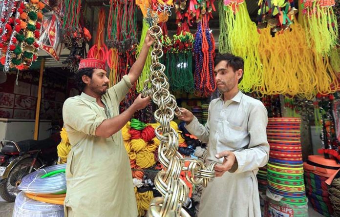 A vendor displays colorful decorative accessories for sacrificial animals to sell ahead of Eid-ul-Adha, attracting customers at the Ring Road area