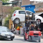 A traffic policeman uses a lifter to remove a wrongly parked vehicle obstructing the flow of traffic