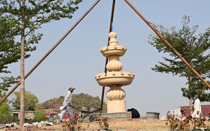 Laborers work on the construction of a fountain under the supervision of CDA near Satra Meel Toll Plaza