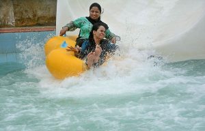 Children enjoy floating on tube boats in a water park pool to beat the heat on a hot summer day.