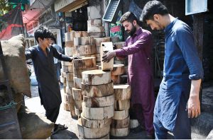 A shopkeeper displays and sells wooden molds for preparing meat ahead of Eid-ul-Adha outside his shop at Sodiwal