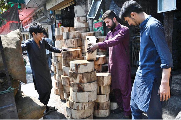 A shopkeeper displays and sells wooden molds for preparing meat ahead of Eid-ul-Adha outside his shop at Sodiwal