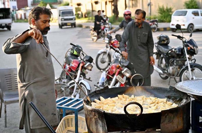A vendor busy frying traditional food item Samosa near F-6 area in the Federal Capital