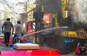 A firefighter extinguishes a fire that erupted in the Saddar Electronic Market