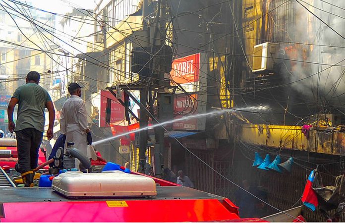 A firefighter extinguishes a fire that erupted in the Saddar Electronic Market