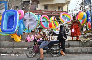 A woman sells inflatable children's swimming pools, air-filled toys, and other items at a roadside stall amid high demand during summer vacations in the city