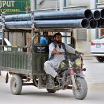 Tricycle rickshaw holder on the way loaded with plastic pipes at Latifabad