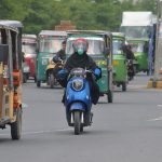 A lady commuter rides an eco-friendly electric scooter on the busy Khanewal Road of the city