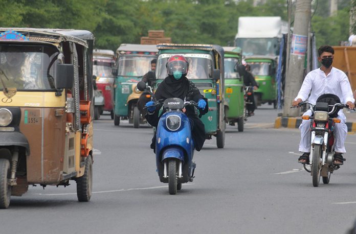 A lady commuter rides an eco-friendly electric scooter on the busy Khanewal Road of the city