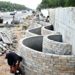 Labourers are busy construction work of a boundary wall along Srinagar Highway, part of efforts to enhance the beauty of Federal Capital