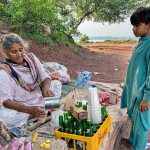 An elderly woman vendor prepares a summer drink for customers at her roadside stall in the Federal Capital