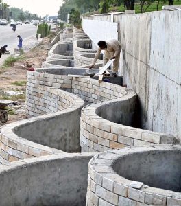Labourers are busy construction work of a boundary wall along Srinagar Highway, part of efforts to enhance the beauty of Federal Capital