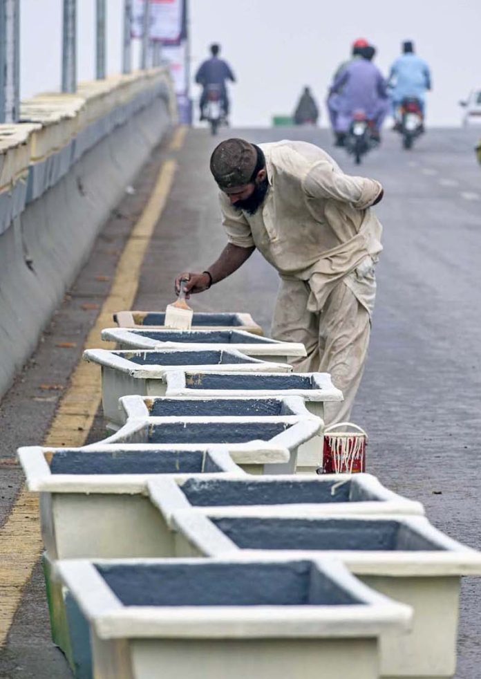 A labourer busy paint the plant pots at 6th Road overhead bridge