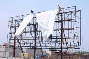 Workers install an advertising banner on a billboard at Chungi No. 09