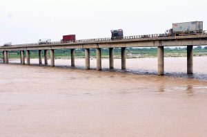 Vehicles are passing over the bridge in the Bypass area as the water level of the Indus River has risen due to recent monsoon rains in the country.