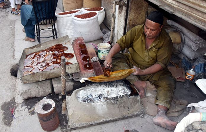 A hardworking craftsman prepares furniture polish using traditional methods at his workplace