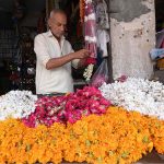 An old man busy in making flower garlands for a customer at Fawara Chowk