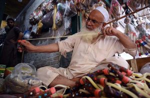 An elderly man busy crafting slingshots at his roadside workplace near the Dabgari area.