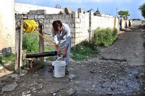 A person fill pot after fetching water from a well in Golra, the Federal Capital