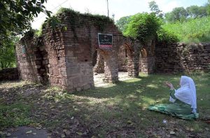 A woman explores the ruins of an ancient mosque situated at the premises of Lotus Lake in the capital. The centuries old abandoned structure was discovered during the development work of the lake in year 2020 in the area, once known as Parian village. The Bunyan tree grown adjacent to the mosque is believed to be some 500 years old.