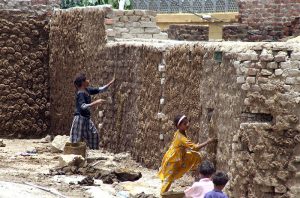 Young girls paste dung cakes on the walls of houses to dry them, which will later be used as fuel for burning at Tando Hyder.