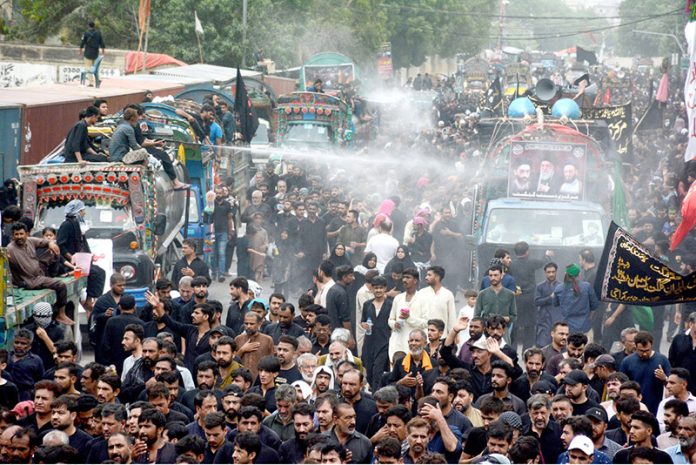 Volunteers uses cannons to spray water on mourners to get relief from the heat during the 10th Ashura procession to commemorate the death anniversary of Hazrat Imam Hussein, the grandson of prophet Muhammad (PBUH) and his companion, who were martyred in the battle of Karbala, Iraq