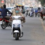 A lady commuter rides an eco-friendly electric scooter on the busy Khanewal road of the city