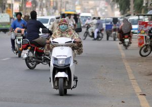 A lady commuter rides an eco-friendly electric scooter on the busy Khanewal road of the city