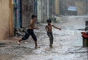 Boys enjoy play in the street during heavy Monsoon rain in the city.