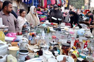 Women busy selecting and purchasing cutlery and utensils from a roadside stall