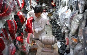 A worker is busy buffering a vehicle's headlight at his workplace.