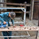 A young worker busy in preparing design on the wood with help of machine at his workplace