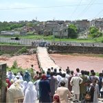 A large crowd has gathered along the Korang Nullah at Sharifabad in the Federal Capital as water levels rose following recent rains. Security personnel are preventing people from crossing the bridge after a young man drowned in the nullah