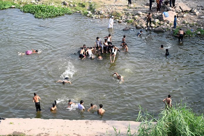Youngsters enjoy bathing in Korang Nallah near Chak Shahzad to find relief from hot weather in the Federal Capital