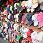 A vendor waits for customers at his roadside stall, displaying colorful caps to attract attention