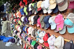 A vendor waits for customers at his roadside stall, displaying colorful caps to attract attention